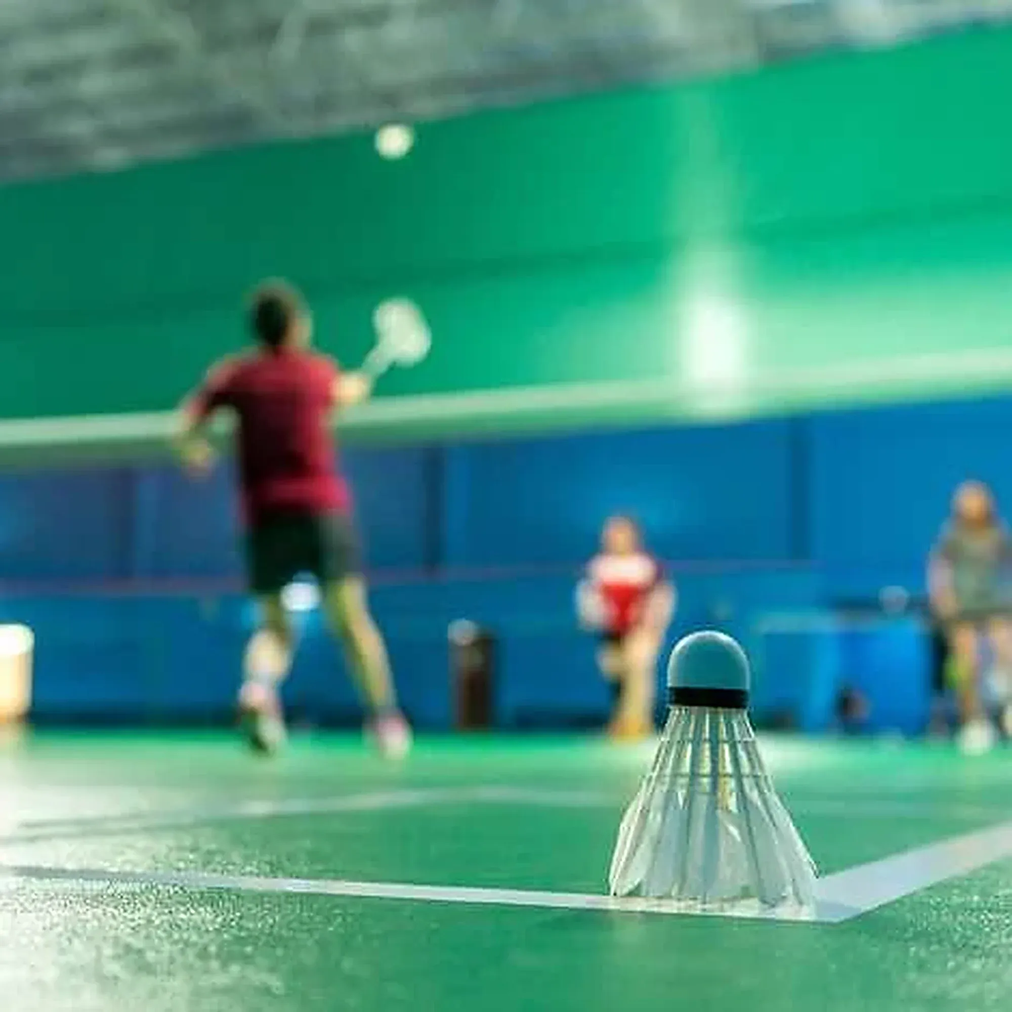 A rally on a busy hall court, shuttles on the floor